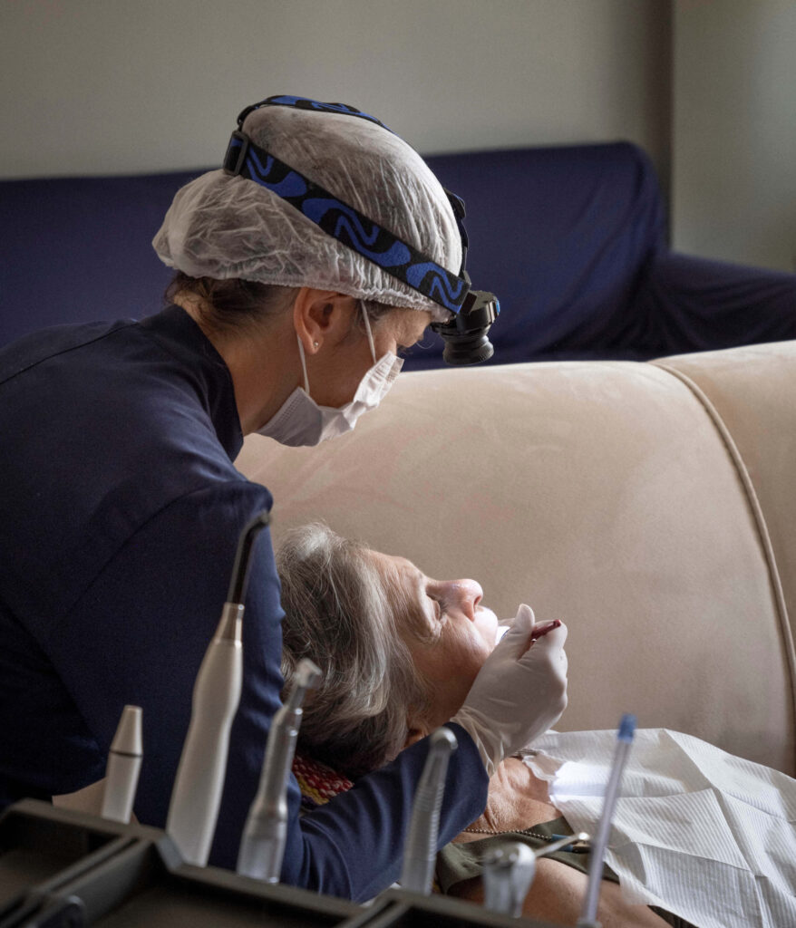 Dentista realizando atendimento odontológico domiciliar em idoso